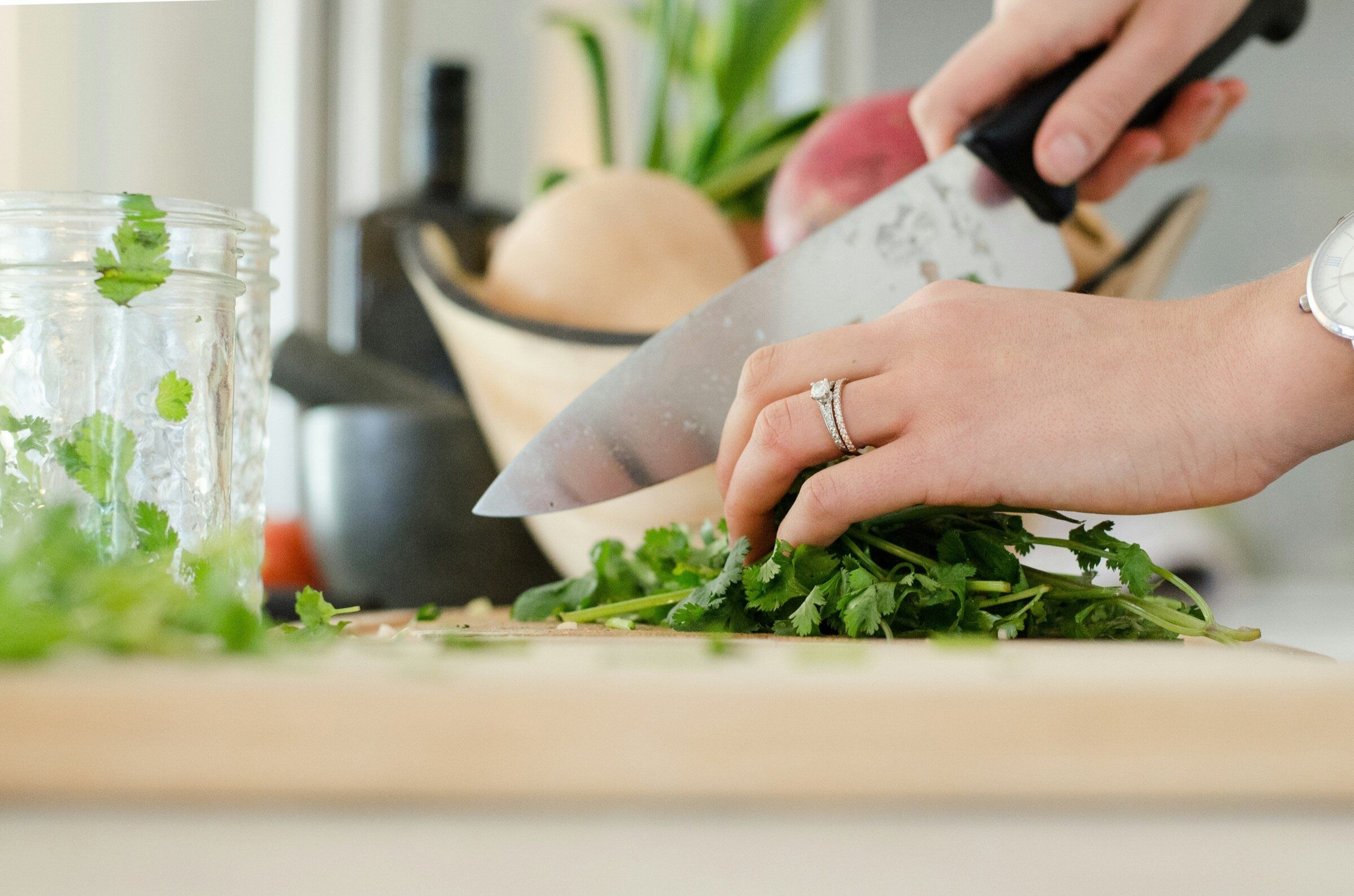 Hands chopping fresh herbs with a chef knife