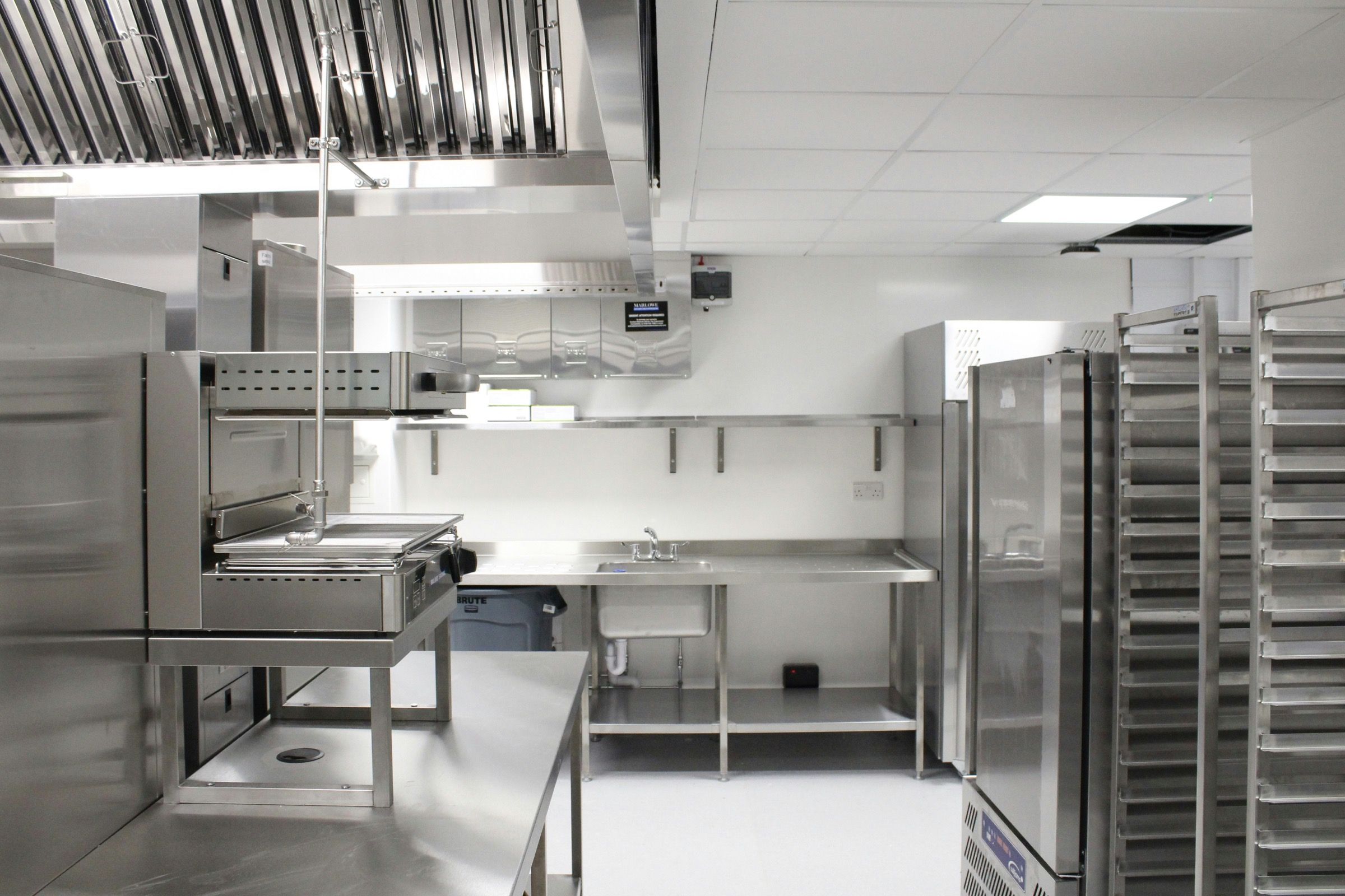 A clean commercial kitchen with stainless steel fridges and benches.